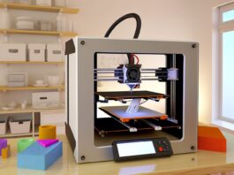 High-resolution realistic photograph of a 3D printer model like the Anycubic Kobra 2 Pro or Elegoo Neptune 4 Pro on a workbench in a home or studio setting, with natural lighting and visible printed objects nearby. Avoid futuristic or stylized elements.